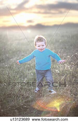 Stock Photo - Toddler boy playing in grassy field. Fotosearch