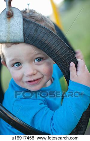Stock Photo - Toddler boy sitting in swing outdoors. Fotosearch