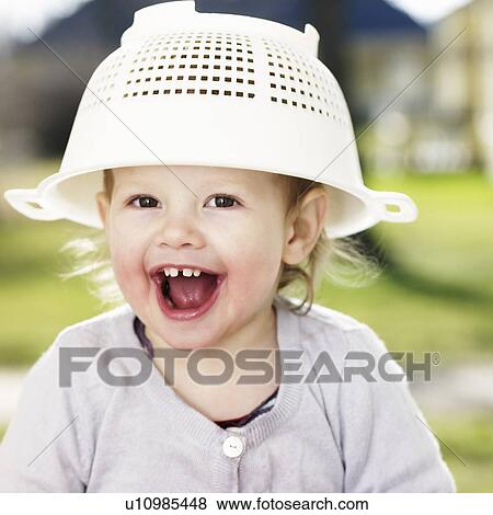 Stock Photo - Toddler girl playing with sieve. Fotosearch