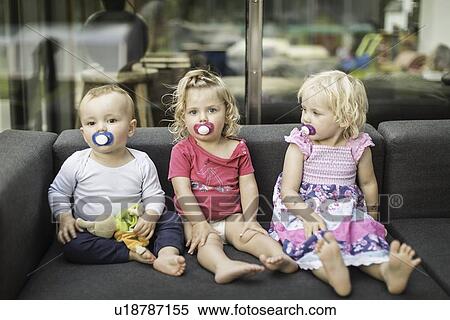 Stock Photography - Toddlers sucking on pacifiers together. Fotosearch