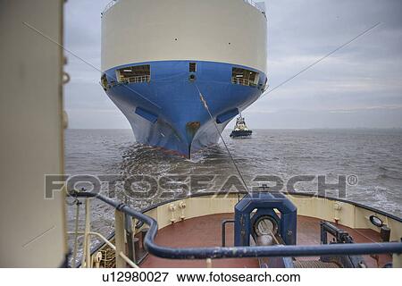 Stock Photo - Tugboat pulling ship to harbor. Fotosearch