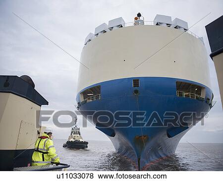 Tugboat sailing by large ship View Large Photo Image Stock Photo - Tugboat sailing by large ship. Fotosearch