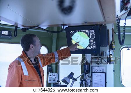 Stock Photography - Tugboat worker examining map. Fotosearch