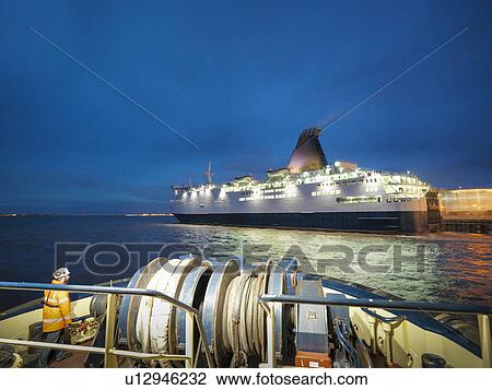 Stock Image - Tugboat worker standing on deck. Fotosearch
