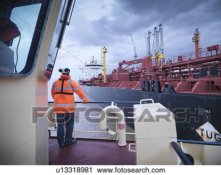 Tugboat worker standing on deck View Large Photo Image Stock Image - Tugboat worker standing on deck. Fotosearch