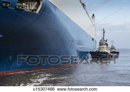 Tugboats pushing car ship View Large Photo Image Stock Photograph - Tugboats pushing car ship. Fotosearch
