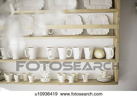 Stock Photo - White coffee cups on kitchen shelf. Fotosearch