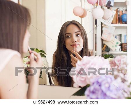 Stock Photo - Woman applying make up in mirror. Fotosearch