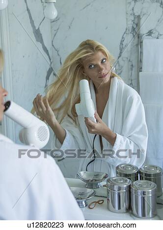 Woman blow drying her hair in bathroom View Large Photo Image Stock Image - Woman blow drying her hair in bathroom. Fotosearch