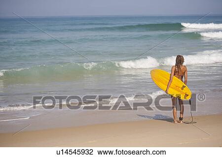 Woman carrying surfboard on beach View Large Photo Image Stock Image - Woman carrying surfboard on beach. Fotosearch