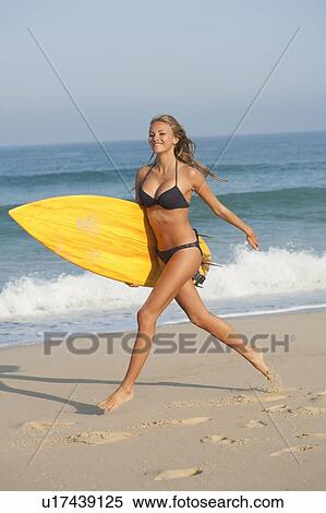Woman carrying surfboard on beach View Large Photo Image Stock Photography - Woman carrying surfboard on beach. Fotosearch