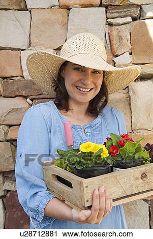 Stock Image - Woman carrying wooden box of flowers. Fotosearch