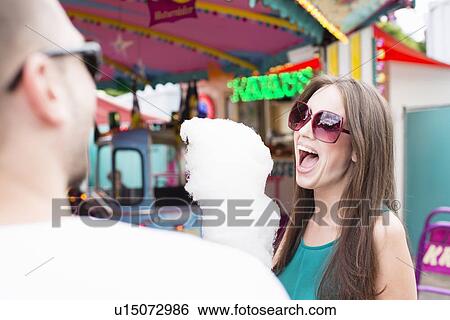Stock Photograph - Woman eating cotton candy at fair. Fotosearch