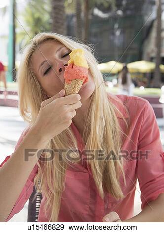 Stock Photo - Woman eating ice cream cone outdoors. Fotosearch
