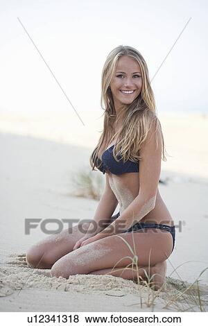 Stock Photo - Woman in bikini sitting on beach. Fotosearch