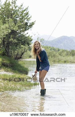 Stock Photo - Woman in boots playing in river. Fotosearch