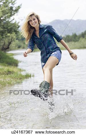 Stock Photo - Woman in boots playing in river. Fotosearch