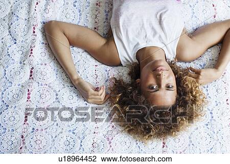 Stock Image - Woman laying on bed. Fotosearch