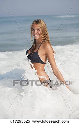 Stock Photography - Woman playing in waves on beach. Fotosearch
