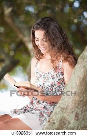Woman reading book in tree outdoors View Large Photo Image Stock Image - Woman reading book in tree outdoors. Fotosearch