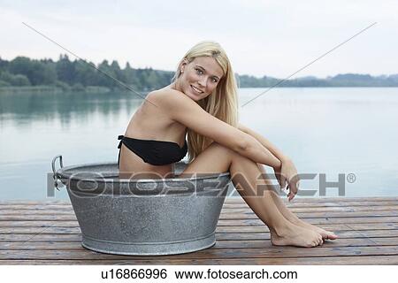 Woman sitting in bucket on wooden deck View Large Photo Image Stock Photograph - Woman sitting in bucket on wooden deck. Fotosearch