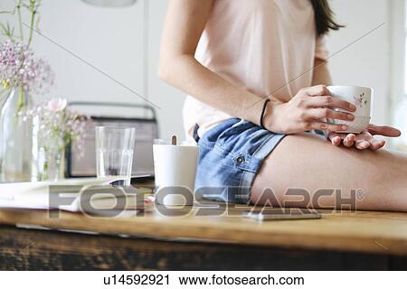 Woman sitting on desk View Large Photo Image Stock Image - Woman sitting on desk. Fotosearch