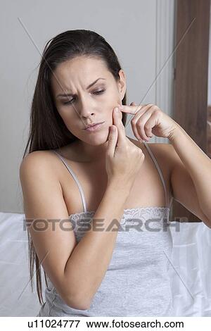 Stock Photo - Woman squeezing spot on face. Fotosearch