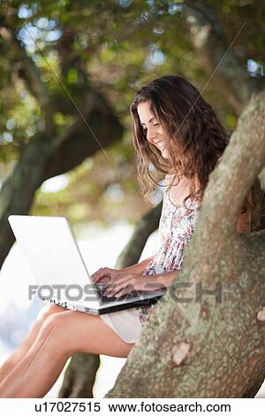 Stock Photography - Woman using laptop in tree outdoors. Fotosearch