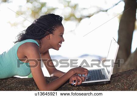 Woman using laptop on a tree branch View Large Photo Image Stock Image - Woman using laptop on a tree branch. Fotosearch