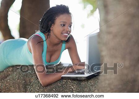 Woman using laptop on a tree branch View Large Photo Image Stock Image - Woman using laptop on a tree branch. Fotosearch