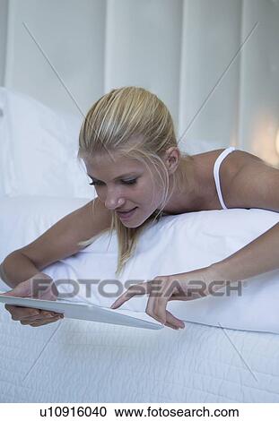 Woman using tablet computer on bed View Large Photo Image Stock Image - Woman using tablet computer on bed. Fotosearch