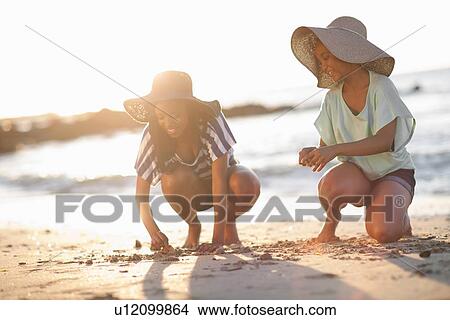 Picture - Women drawing in sand on beach. Fotosearch