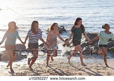 Stock Photo - Women holding hands on beach. Fotosearch