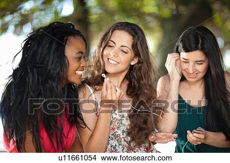 Picture - Women listening to earphones outdoors. Fotosearch