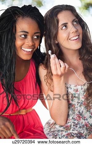 Picture - Women listening to earphones outdoors. Fotosearch