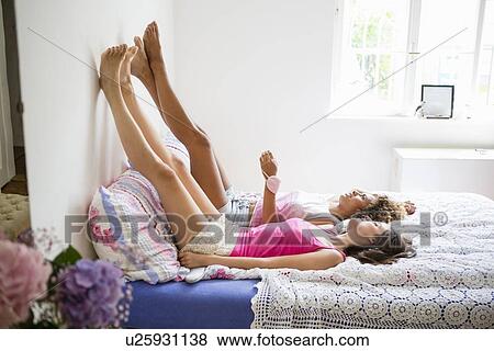 Women relaxing on bed together View Large Photo Image Stock Photo - Women relaxing on bed together. Fotosearch