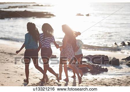 Stock Photograph - Women running together on beach. Fotosearch