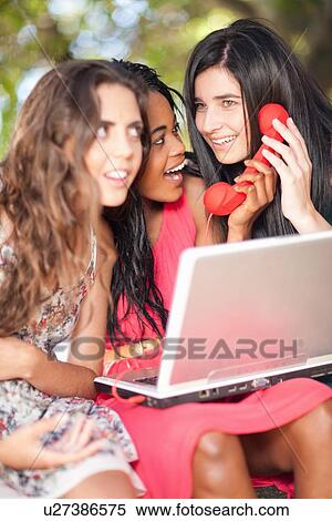 Women using laptop and phone whilst sitting on a tree branch View Large Photo Image Stock Photography - Women using laptop and phone whilst sitting on a tree branch. Fotosearch
