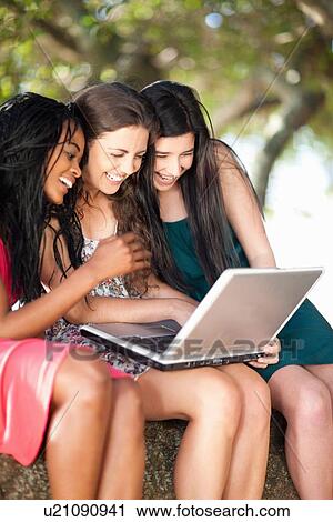 Women using laptop whilst sitting on a tree branch View Large Photo Image Stock Image - Women using laptop whilst sitting on a tree branch. Fotosearch