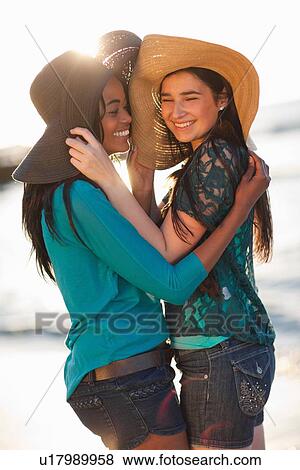 Stock Photo - Women wearing sun hats on beach. Fotosearch