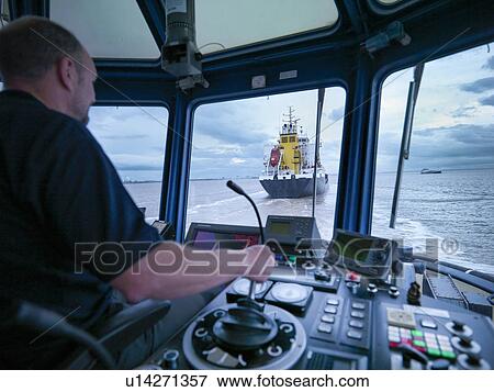 Worker driving tugboat in wheelhouse View Large Photo Image Stock Photo - Worker driving tugboat in wheelhouse. Fotosearch