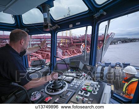 Worker driving tugboat in wheelhouse View Large Photo Image Stock Photograph - Worker driving tugboat in wheelhouse. Fotosearch