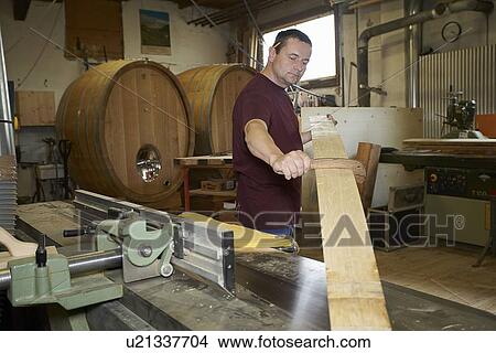 Picture - Worker examining wood in shop. Fotosearch