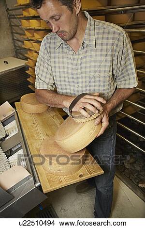 Picture - Worker finishing wheel of cheese in shop. Fotosearch