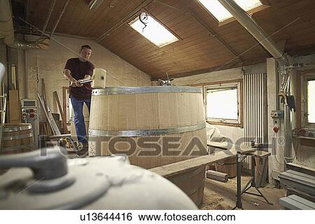Worker hammering barrel in shop View Large Photo Image Stock Photograph - Worker hammering barrel in shop. Fotosearch