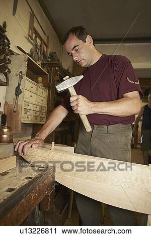 Worker hammering nail into wood View Large Photo Image Stock Image - Worker hammering nail into wood. Fotosearch