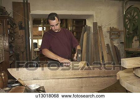 Worker hammering wood in shop View Large Photo Image Stock Photo - Worker hammering wood in shop. Fotosearch