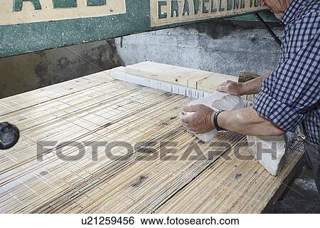 Stock Photograph - Worker laying stone block on board. Fotosearch