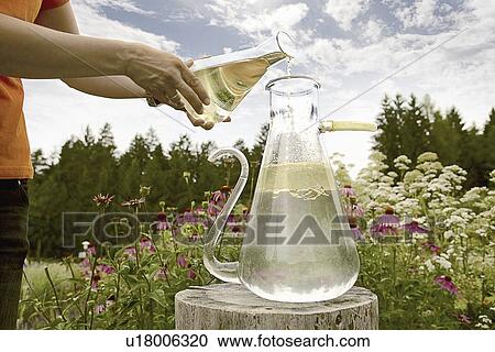 Stock Image - Worker pouring chemicals in field. Fotosearch