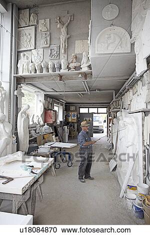 Stock Image - Worker standing in relief carving shop. Fotosearch